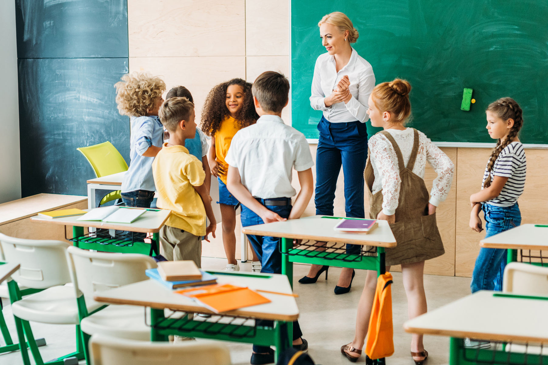 group of classmates standing around teacher at classroom